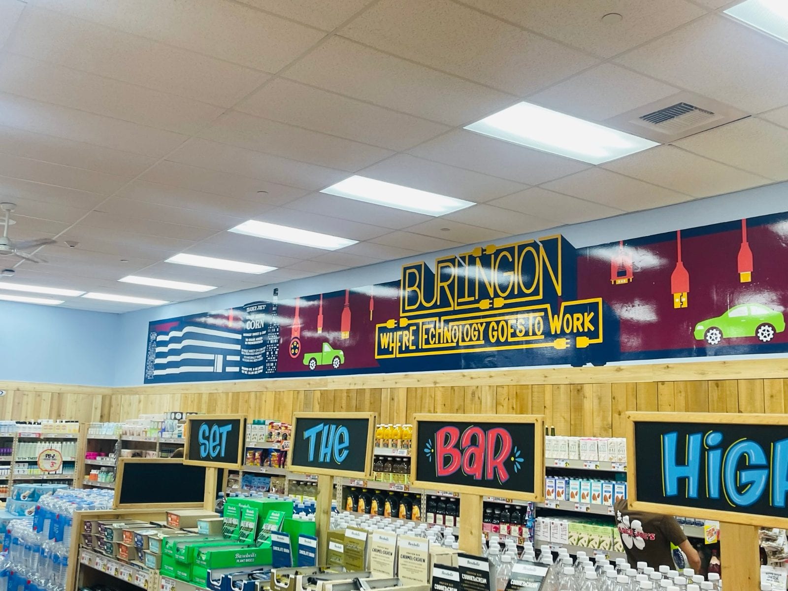 Store-wide printed mural above the aisles, with hand-lettered aisle signs